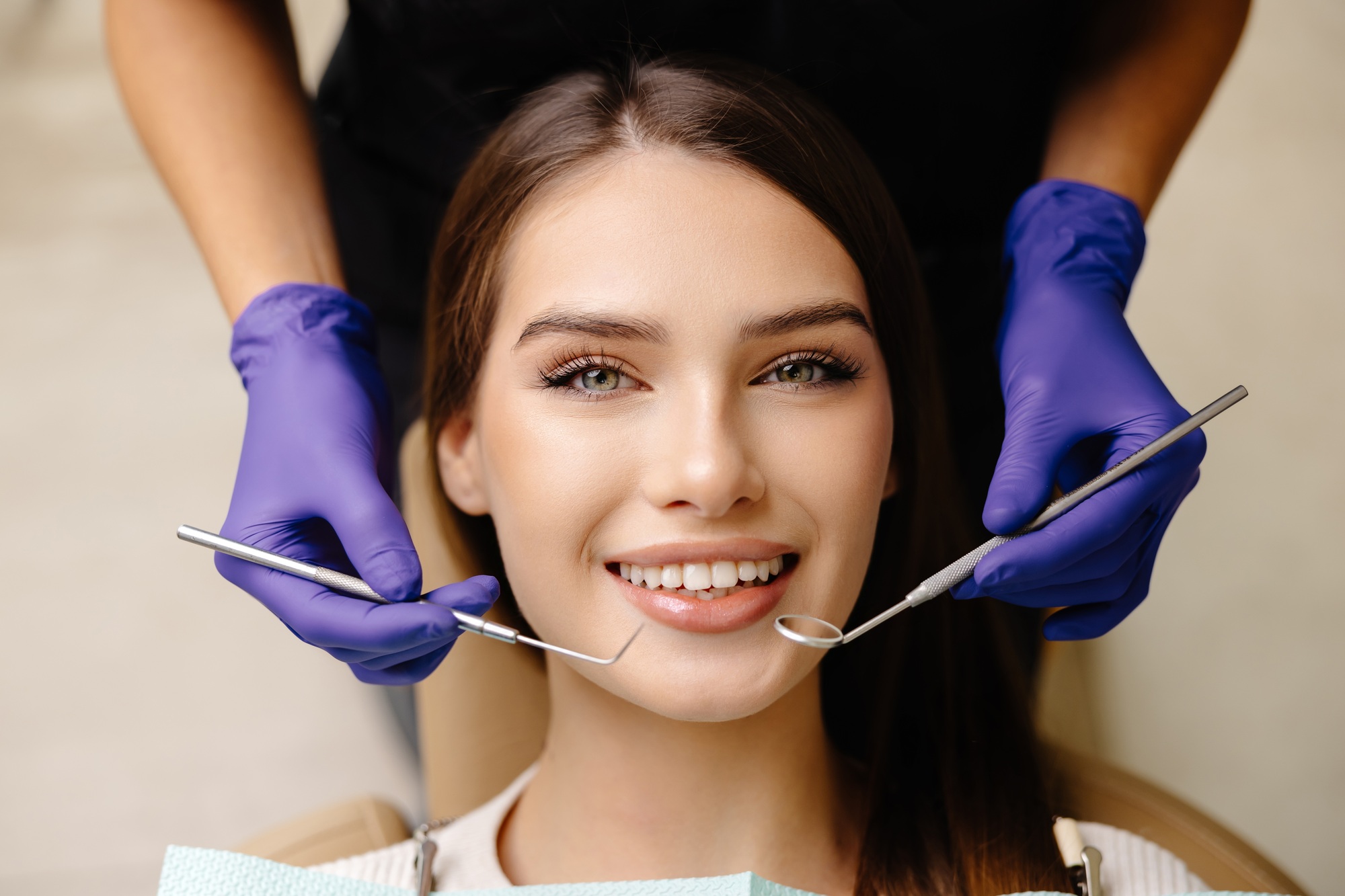 a woman with purple gloves holding tools to her mouth