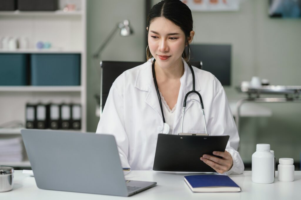 About Us 2 Doctor working on laptop computer and tablet and medical stethoscope on clipboard on desk